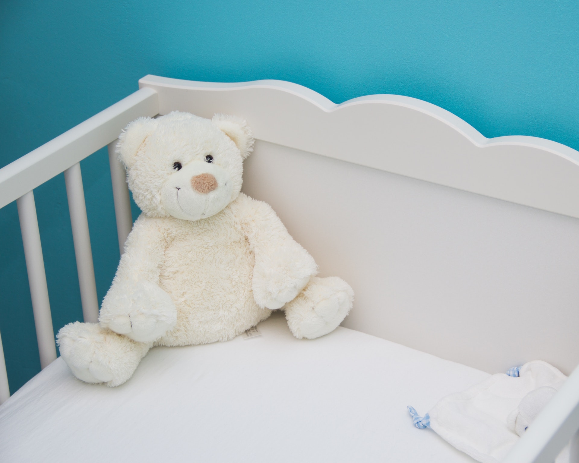 White teddy bear in crib
